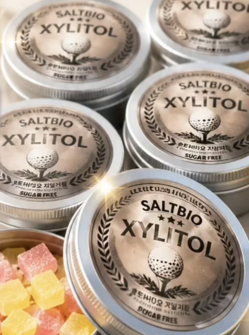 골프공 엠블럼과 SALTBIO XYLITOL 문구를 새긴 은색 틴케이스들